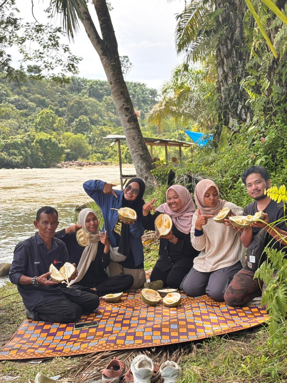 Suasana santai wisatawan yang makan durian di tepi Sungai Sikelang, Subulussalam. (Foto/ist)
